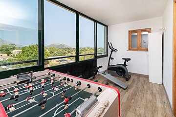 A room with a foosball table and an exercise bike