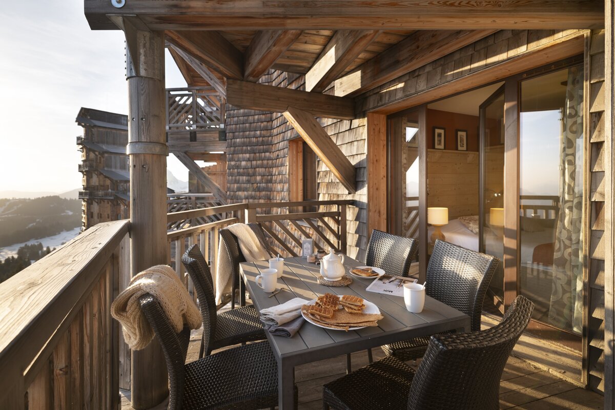 A balcony with a table and chairs with a plate of waffles on it