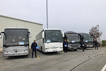 A group of mercedes buses are parked in a parking lot