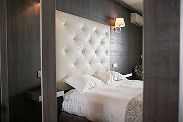 A hotel room with a bed and a lamp on the wall