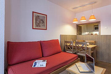 A living room with a red couch and a laptop on a table