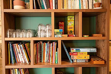 A bookshelf with books and games including risk