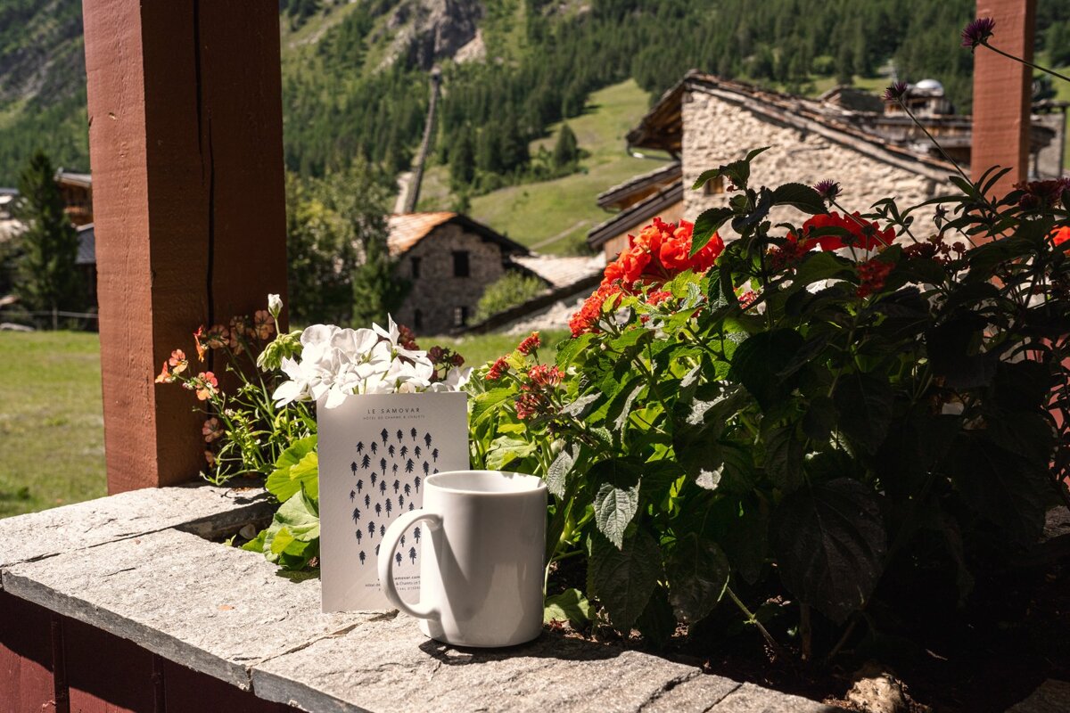A white mug sits on a ledge next to a book that says le caravane