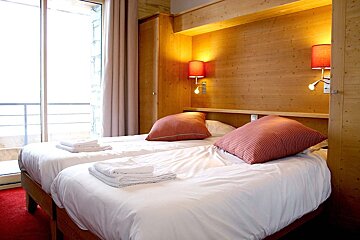 A hotel room with two beds and two lamps