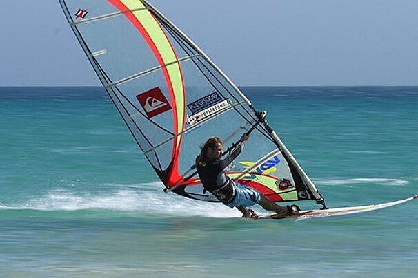 A man sails a quiksilver sail in the ocean