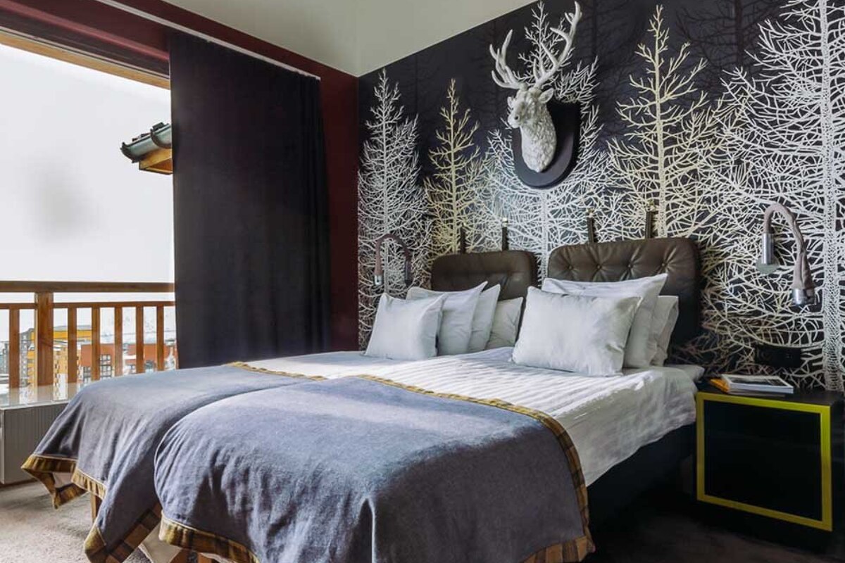 A hotel room with two beds and a deer head on the wall