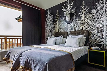 A hotel room with two beds and a deer head on the wall