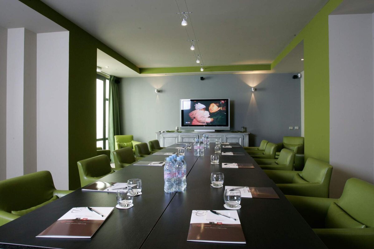 A conference room with a long table and green chairs