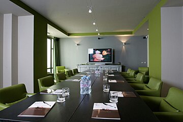 A conference room with a long table and green chairs