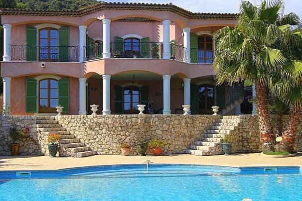 A large pink house with a swimming pool in front of it
