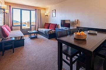 A bowl of oranges sits on a table in a living room