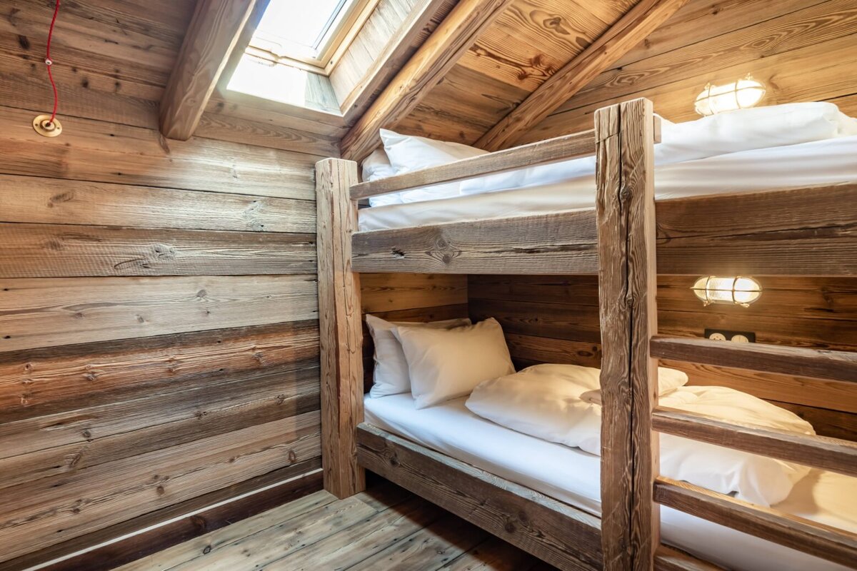 A wooden bunk bed with white sheets and pillows