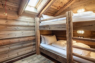 A wooden bunk bed with white sheets and pillows