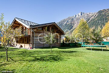 A large wooden house with a trampoline in front of it