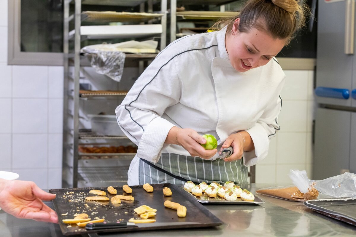 A woman in a chef 's coat is making a dessert