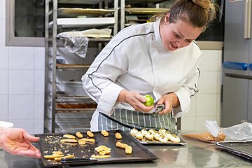 A woman in a chef 's coat is making a dessert