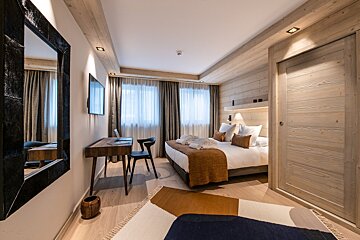 A bedroom with a large bed and a desk