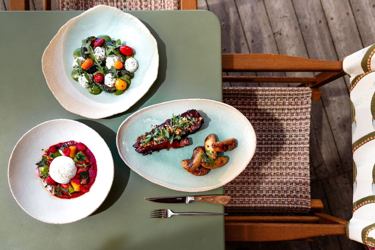 Three plates of food are on a green table