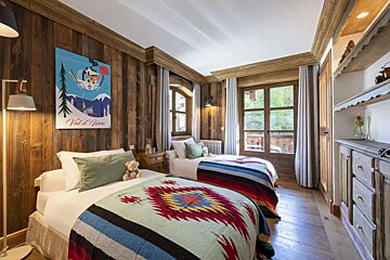 A bedroom with two beds and a poster on the wall that says val d' ivre