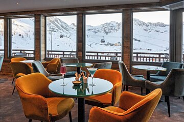 A restaurant with tables and chairs with a view of mountains