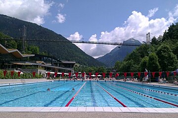 an outdoor swimming pool with a bridge behind