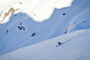 a skier in the shadow of the mountains