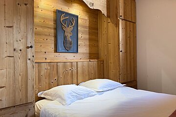 A bedroom with a bed and a painting of a deer on the wall