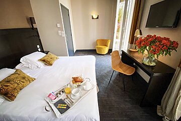 A hotel room with a tray of food on the bed