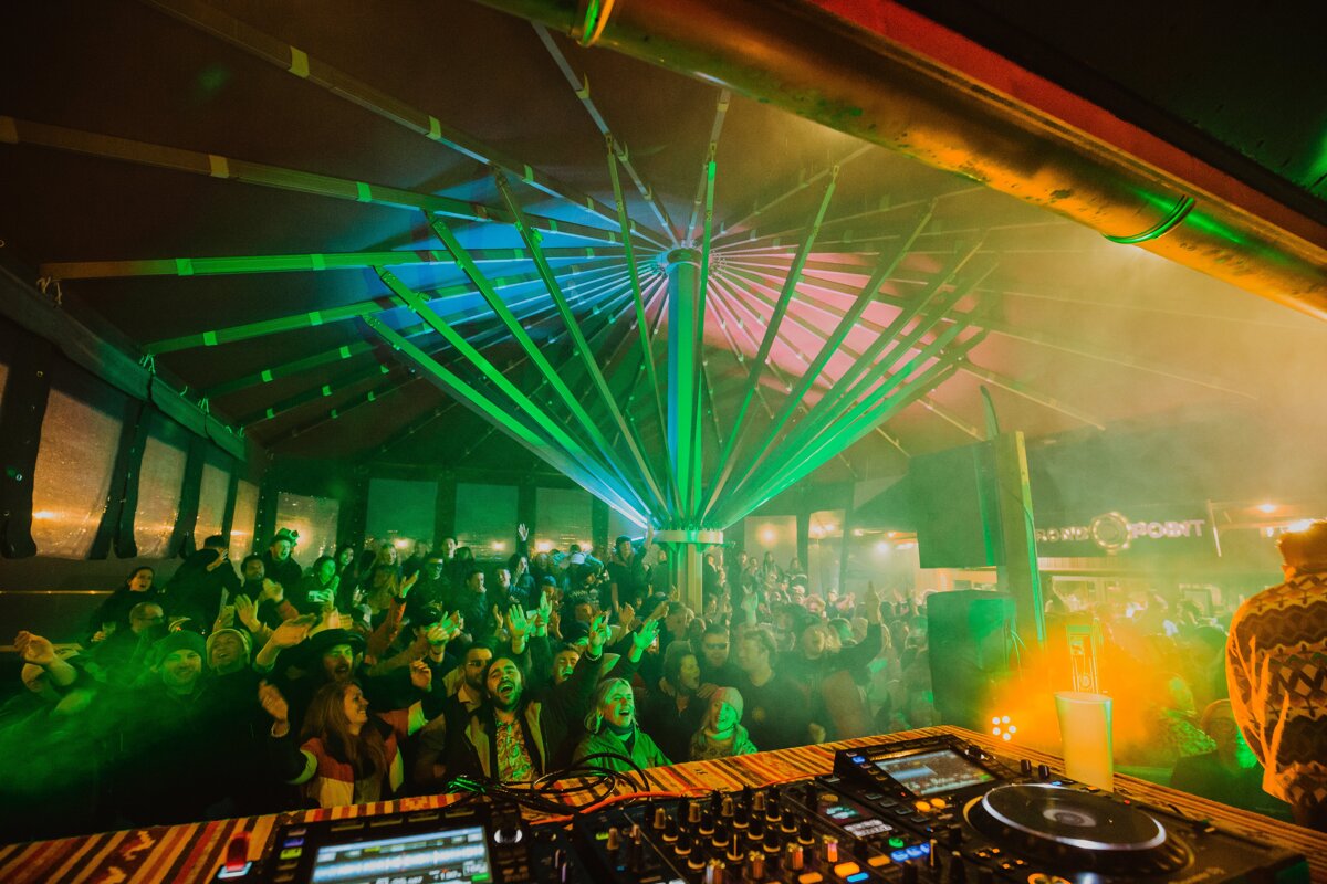 A crowd of people watching a dj at a music festival