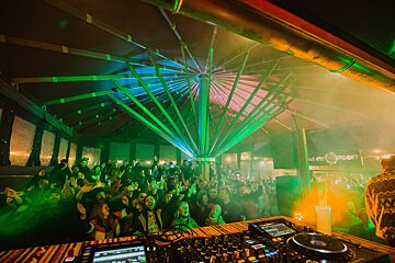 A crowd of people watching a dj at a music festival