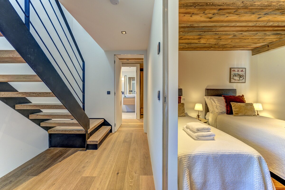 A bedroom with two beds and a staircase leading up to it