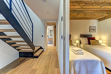 A bedroom with two beds and a staircase leading up to it