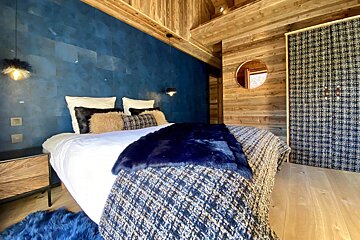A bedroom with blue walls and a bed with a blue blanket