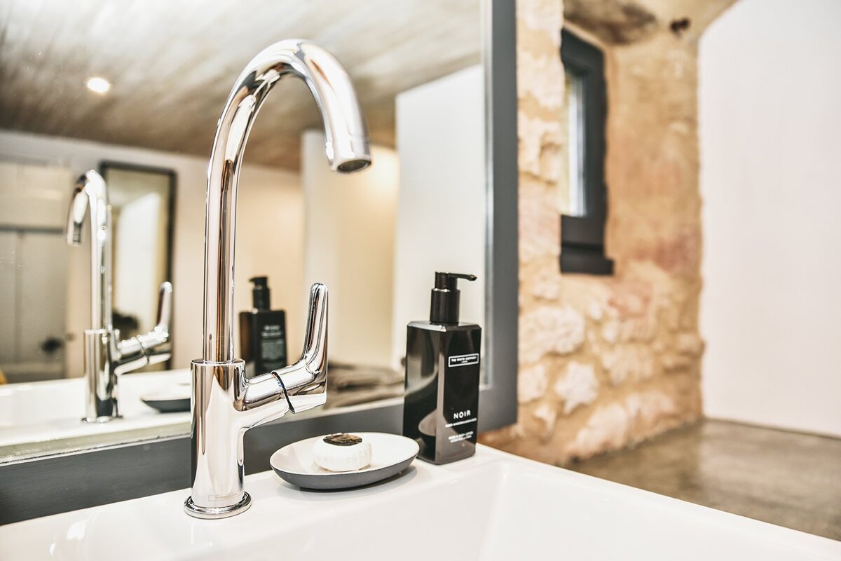 A bathroom sink with a soap dish and a bottle of aqua