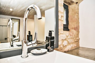 A bathroom sink with a soap dish and a bottle of aqua