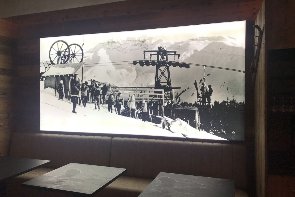 A black and white photo of skiers on a ski lift