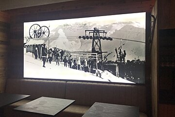 A black and white photo of skiers on a ski lift
