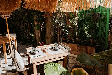 A wooden table with plates and glasses under a thatched umbrella with a sign that says lounge