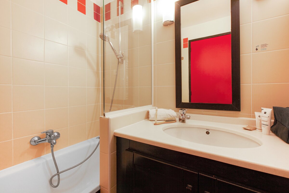 A bathroom with a sink and a red mirror