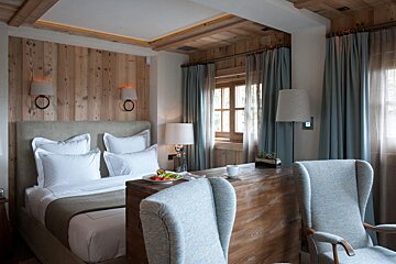 A bedroom with a large bed and two chairs