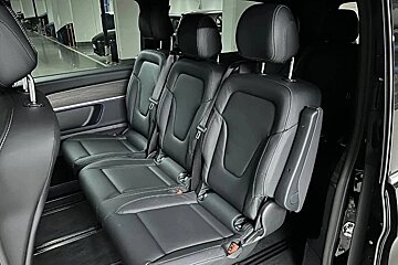 Three black leather individual passenger seats with headrests and seatbelts are visible in the interior of a vehicle, likely a van or SUV.