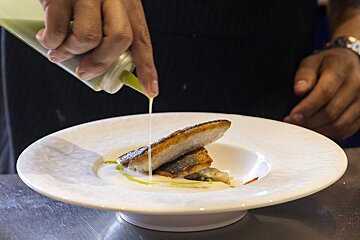 A person pouring sauce on a plate of food