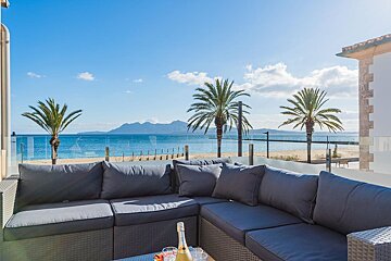 A balcony with a view of the ocean and palm trees