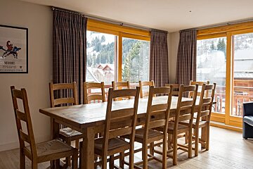 A dining room with a table and chairs and a poster on the wall that says olympics
