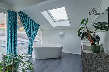A bathtub in a bathroom with a skylight above it