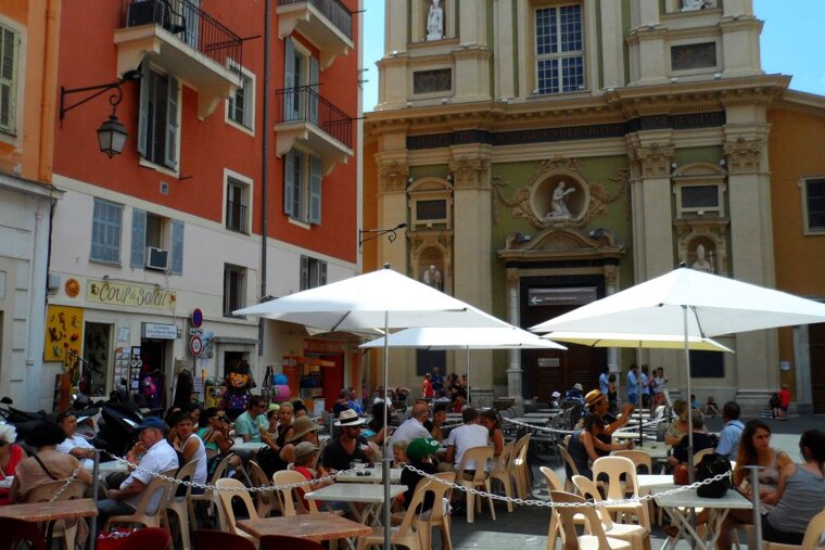 people sitting a cafes in a square in old nice
