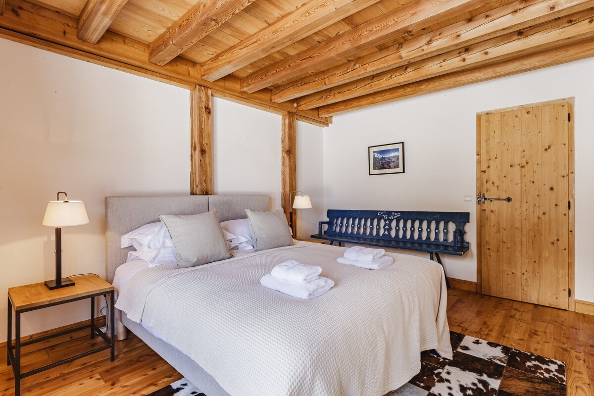 A bedroom with a king size bed and a blue bench with the word lodge on it