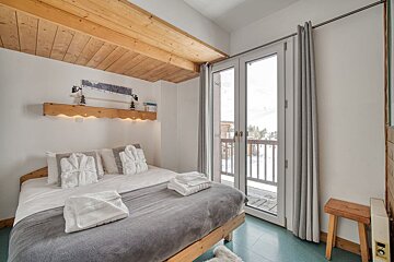 A bedroom with a king size bed and a balcony