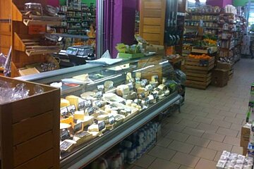 A display case in a grocery store contains a variety of cheeses