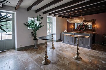 A room with a bar and two tables with candles on them